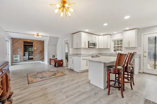 a kitchen with stainless steel appliances granite countertop a stove top oven a sink dishwasher a dining table and chairs with wooden floor