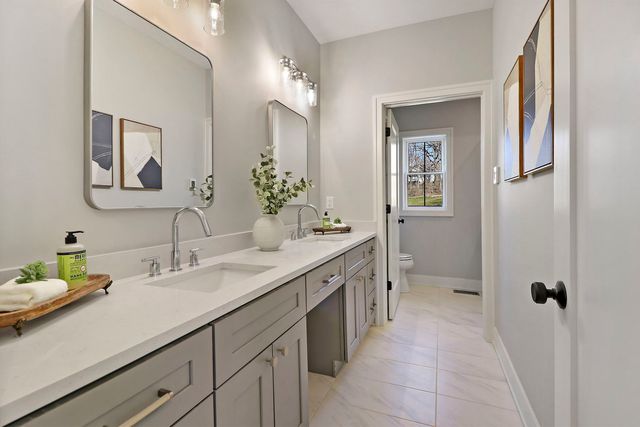 a spacious bathroom with a granite countertop sink a toilet a mirror and shower