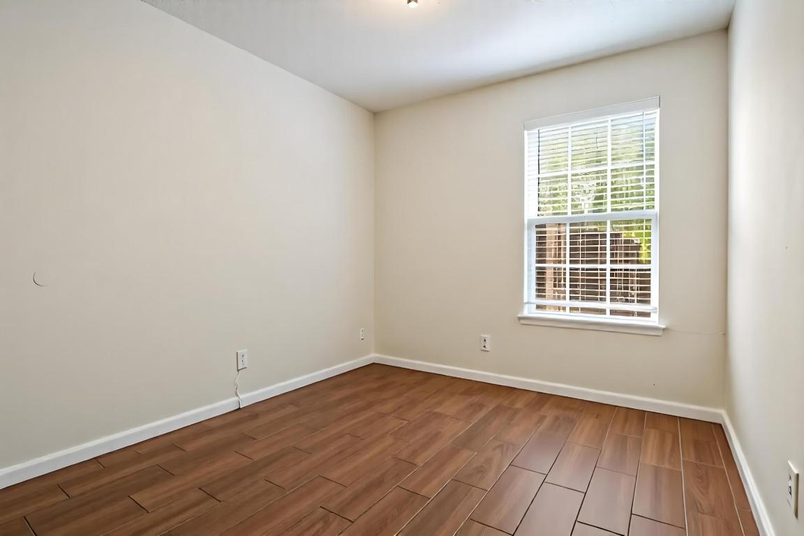 1115 Brookswood Avenue, Unit B Austin, TX 78721 - Photo 18 of 34 an empty room with wooden floor and windows