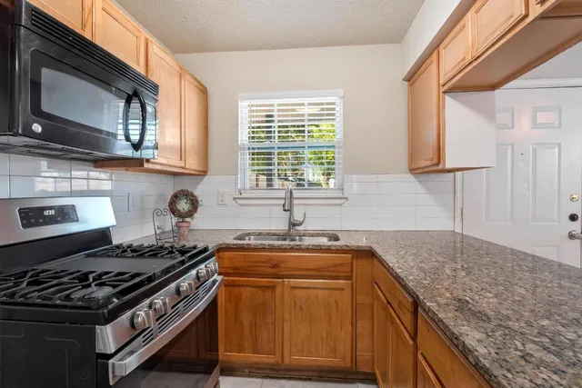 a kitchen with stainless steel appliances granite countertop a sink stove and a granite counter top