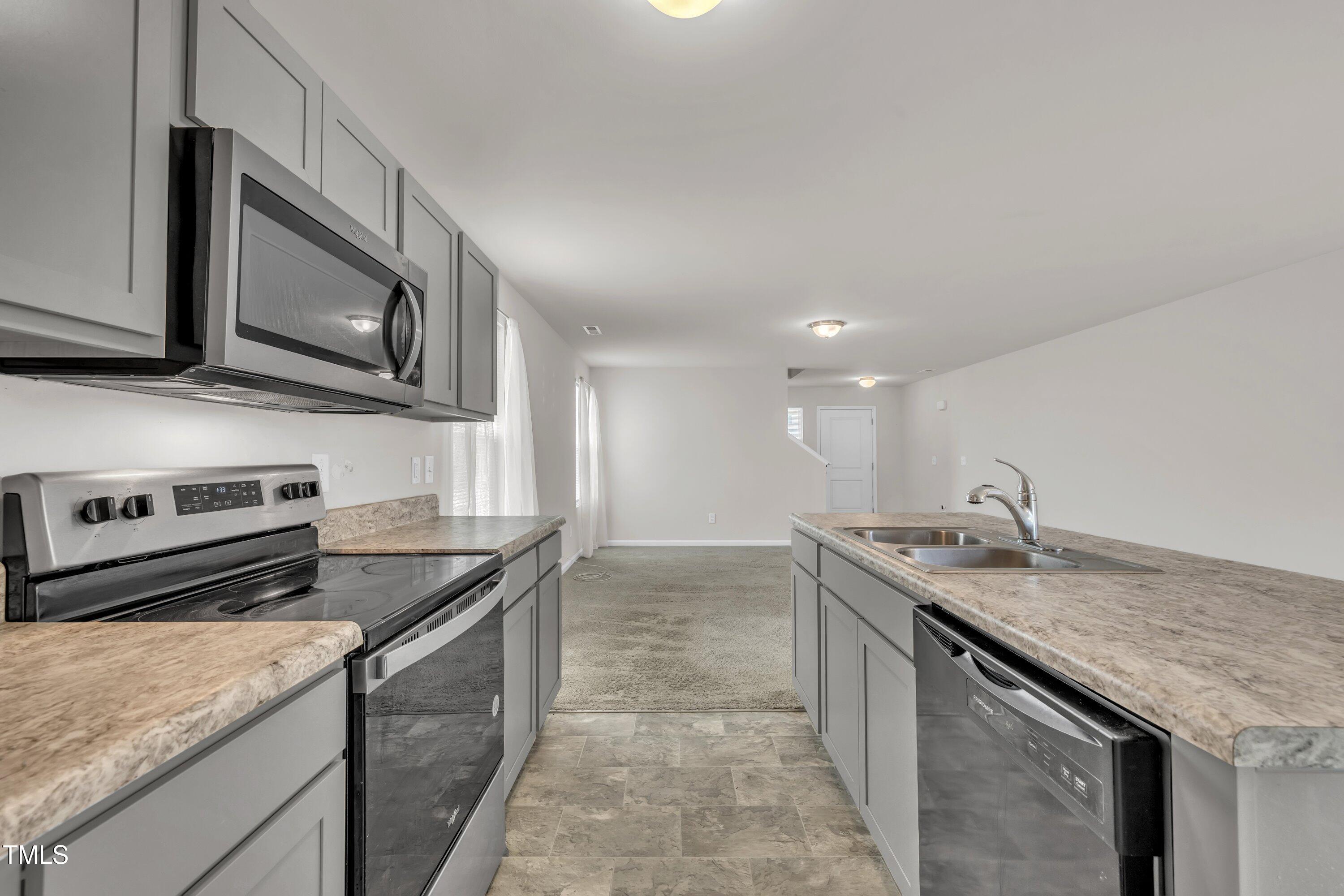 146 Maple Tree Lane Clayton, NC 27527 - Photo 18 of 50 a kitchen with stainless steel appliances granite countertop a sink dishwasher stove and microwave with wooden floor
