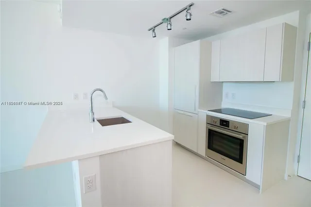a kitchen with a sink stainless steel appliances and white cabinets