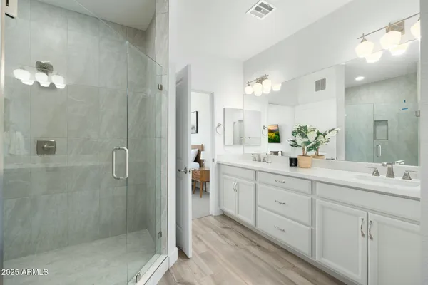 a bathroom with a double vanity sink mirror and shower
