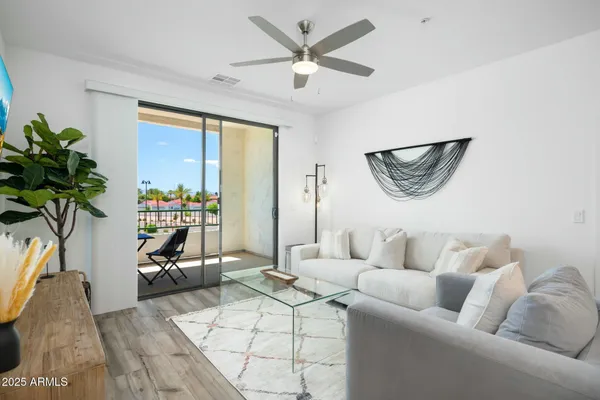a living room with furniture a potted plant and a large window