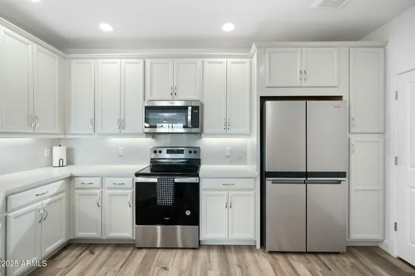 a kitchen with white cabinets and stainless steel appliances