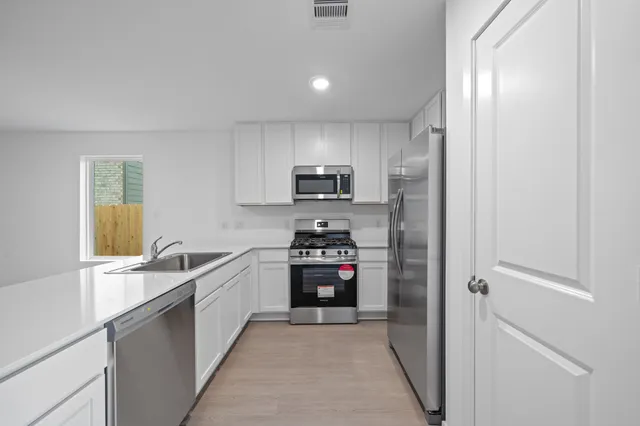a kitchen with granite countertop white cabinets and stainless steel appliances