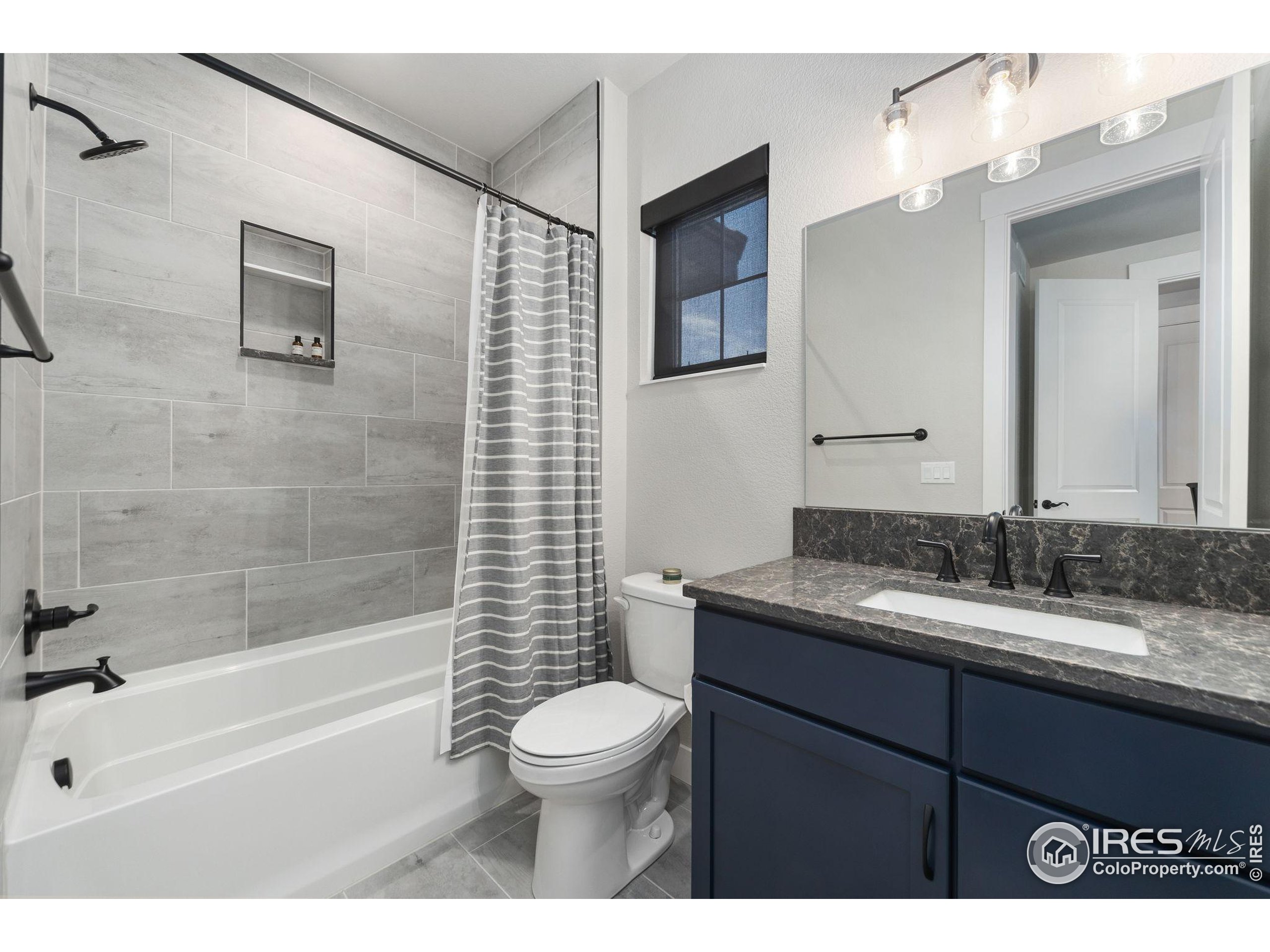 2748 Prairie Flax Street Berthoud, CO 80513 - Photo 22 of 40 a bathroom with a granite countertop sink toilet mirror and bathtub