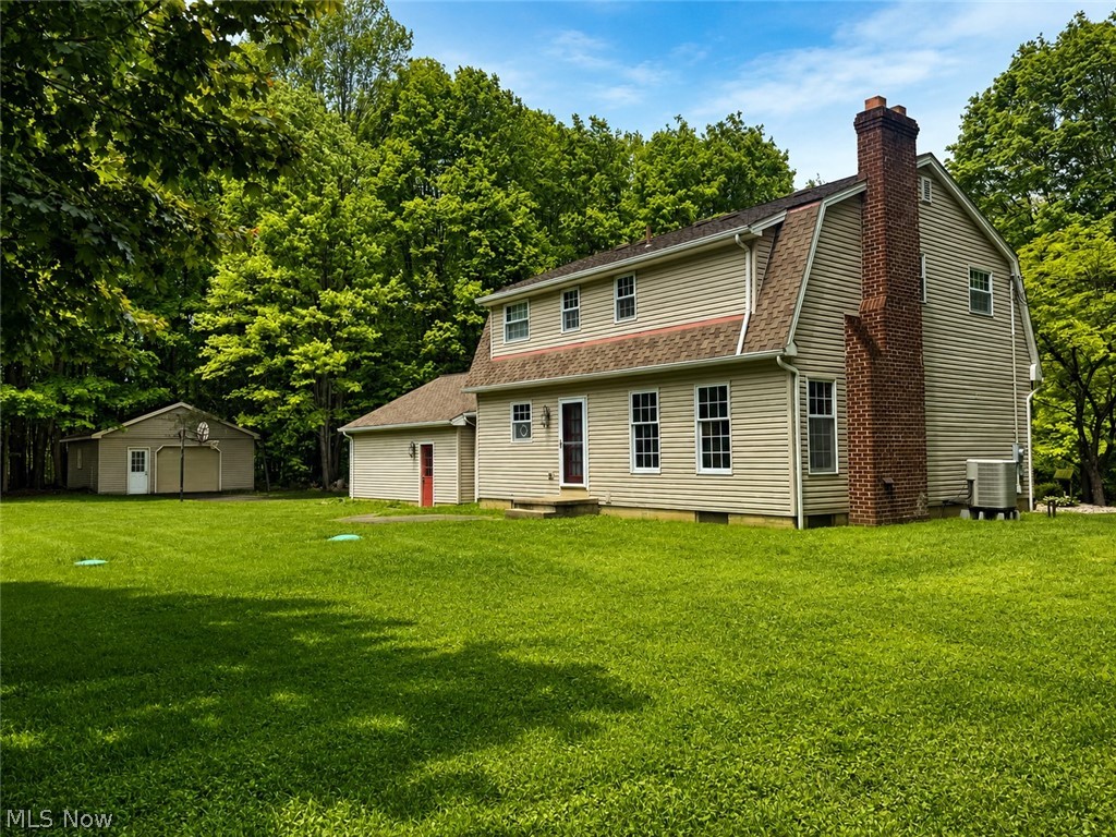 6155 Gibson Road Canfield, OH 44406 - Photo 7 of 43 Spacious rear yard with a two-story residence featuring light-colored siding and a prominent brick chimney