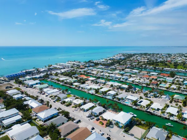 an aerial view of a city with lots of residential buildings and ocean view in back