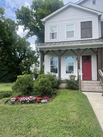 a view of white house with a yard and potted plants