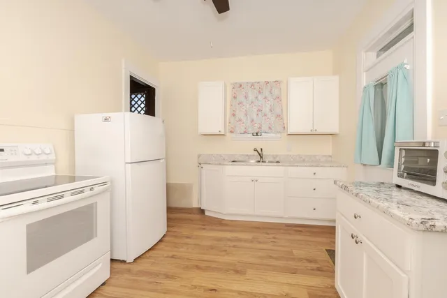 a kitchen with granite countertop white cabinets and white appliances