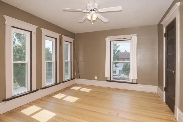 a view of an empty room with window and chandelier fan