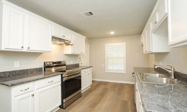 a kitchen with granite countertop a stove a sink and a granite counter tops