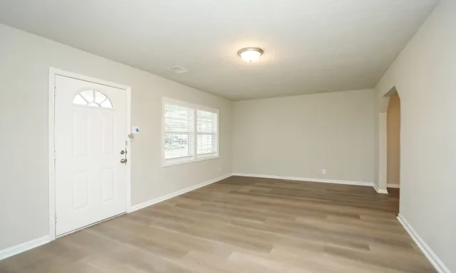 an empty room with wooden floor and windows