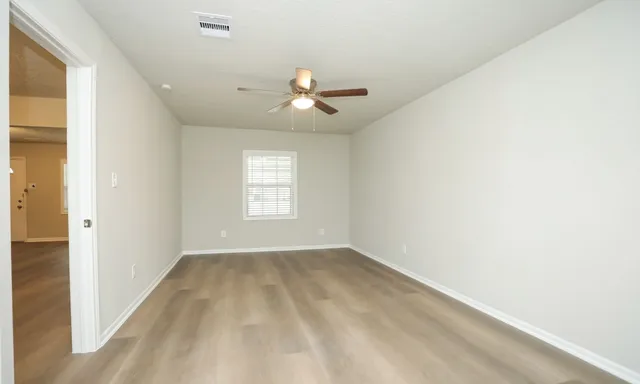 an empty room with windows and fan