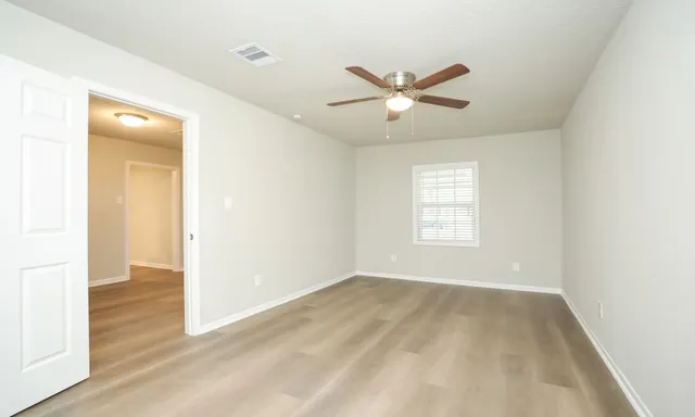 a view of empty room with wooden floor and fan