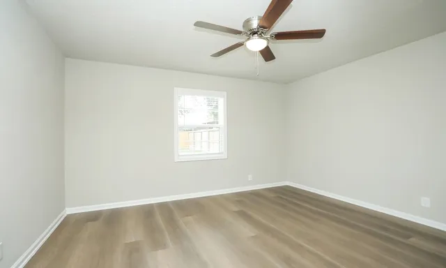 an empty room with a window and a fan