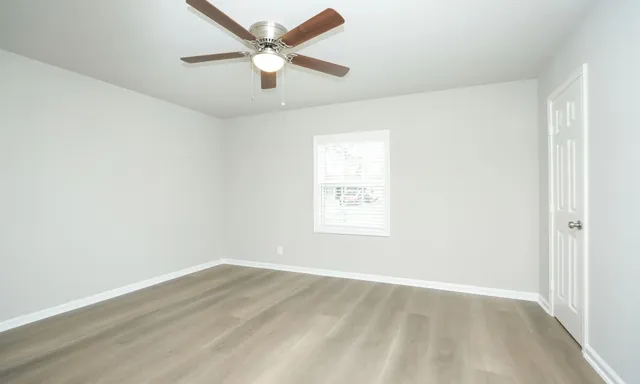 an empty room with a window and a fan