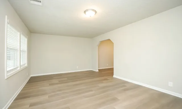 an empty room with wooden floor and windows