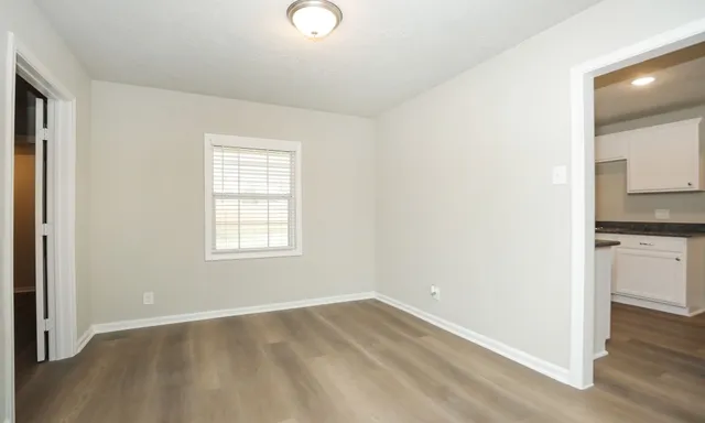 an empty room with wooden floor and a window