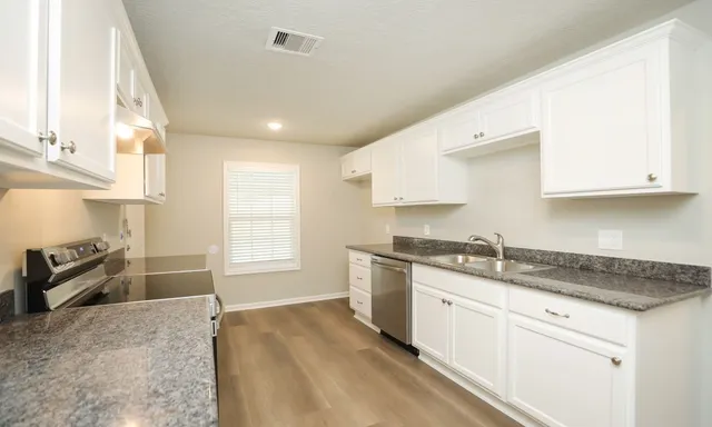 a kitchen with granite countertop white cabinets and stainless steel appliances
