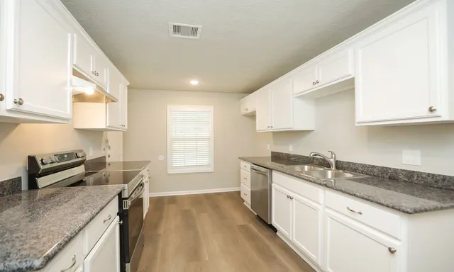 a kitchen with granite countertop a sink a stove and cabinets