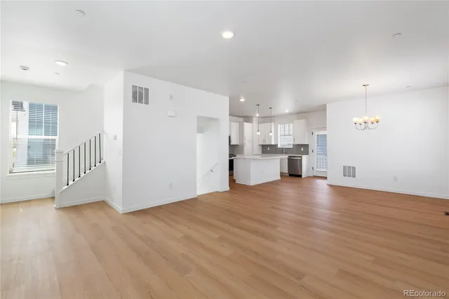 a view of a kitchen with a fridge and wooden floor
