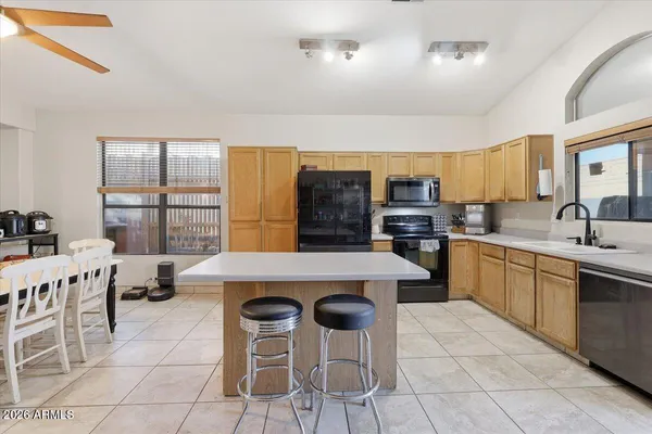 a kitchen with stainless steel appliances granite countertop a stove top oven a sink a dining table and chairs
