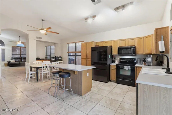 a kitchen with stainless steel appliances kitchen island granite countertop a table chairs microwave and sink