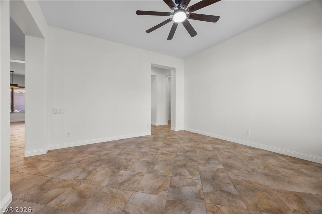 2125 De Rouge Avenue Henderson, NV 89044 - Photo 34 of 96 A spacious room features clean white walls and durable tile flooring, illuminated by a modern ceiling fan.