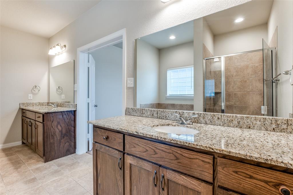 4662 Ralph Lane Dallas, TX 75227 - Photo 16 of 25 Dual vanity sinks with granite countertops, wood-finish cabinetry, tile flooring, and a glass-enclosed shower with tiled walls
