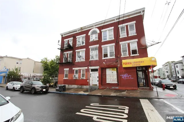 a front view of a building with cars parked