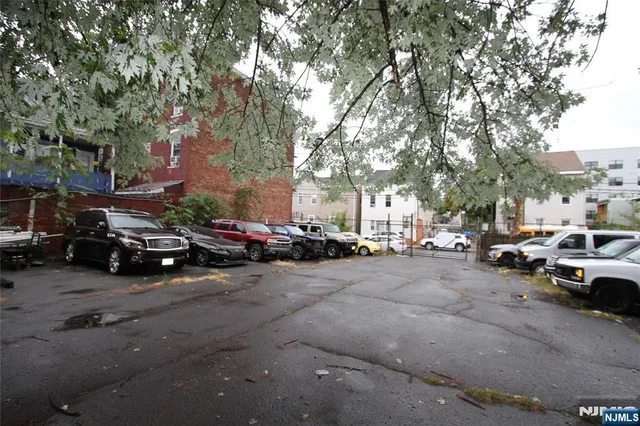 a view of road with card parked on side and retail shops