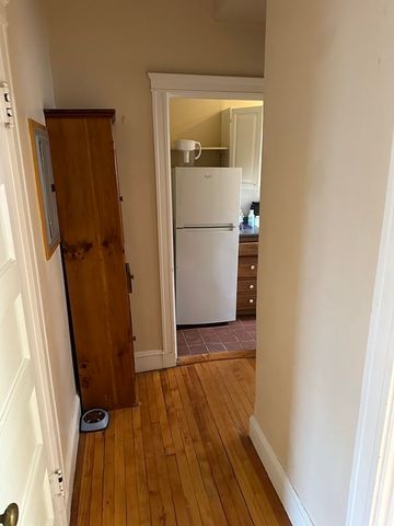 a view of a hallway with wooden floor and cabinets