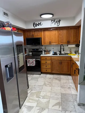 a kitchen with stainless steel appliances a stove a sink a microwave a refrigerator and cabinets