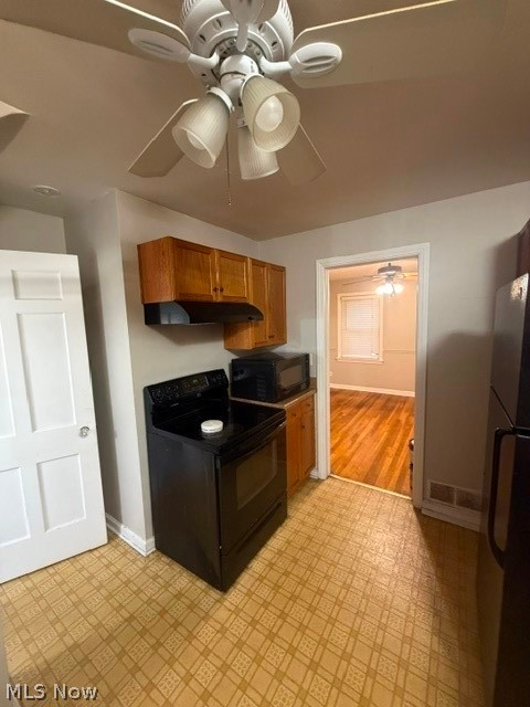 1388 Cranover Road Lyndhurst, OH 44124 - Photo 16 of 35 Kitchen area featuring a ceiling fan with integrated lighting, wood-finish cabinetry, a black range, and patterned flooring