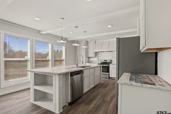 a kitchen with stainless steel appliances granite countertop white cabinets and a window