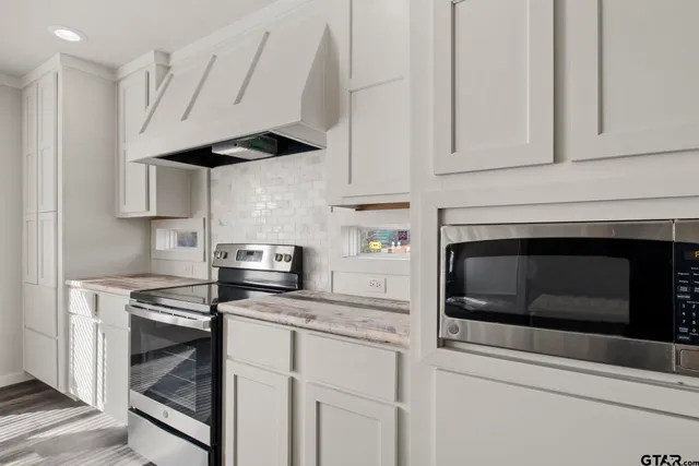 a kitchen with stainless steel appliances white cabinets and a stove a oven with white countertops