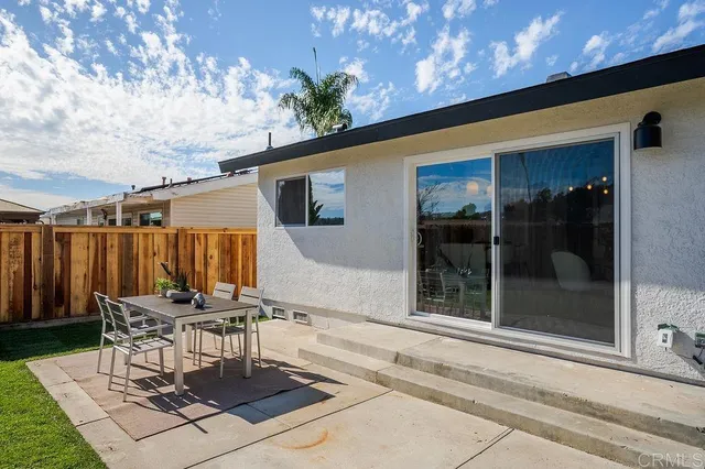 a patio with a table and chairs and potted plants