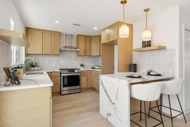 a kitchen with stainless steel appliances granite countertop a sink a stove a refrigerator and island with wooden floor