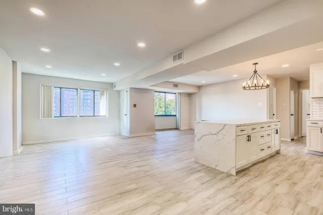 a view of a livingroom with kitchen cabinets and wooden floor