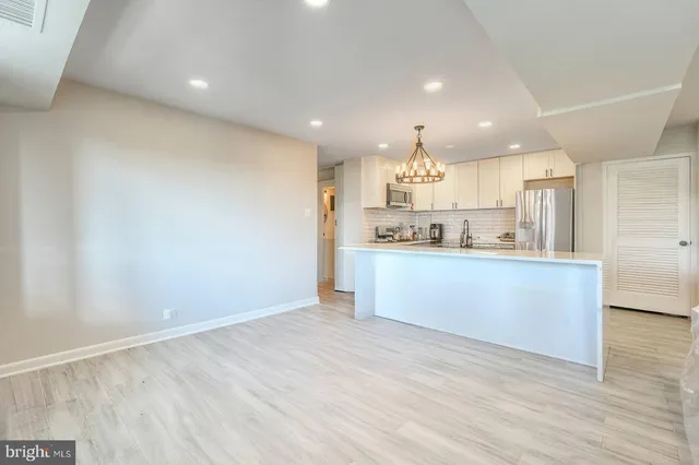 a view of kitchen with kitchen island stainless steel appliances wooden cabinets and wooden floor