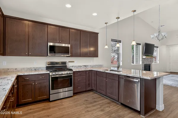 a kitchen with stainless steel appliances a sink a stove a microwave a center island and cabinets