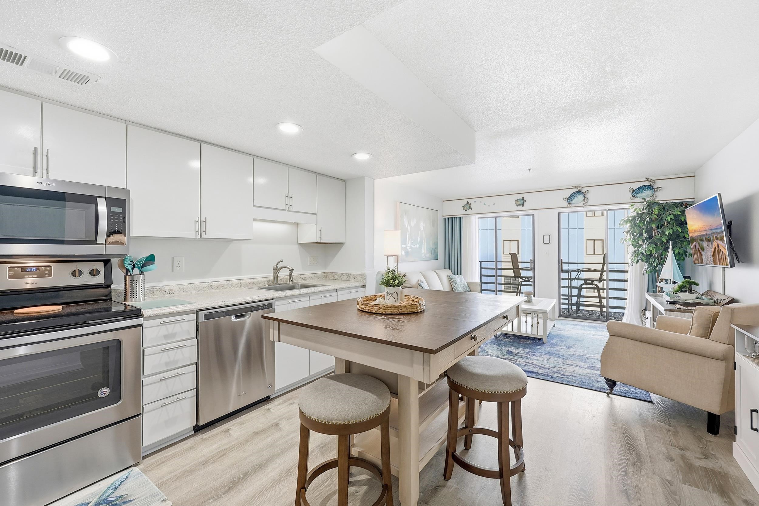 920 North Waccamaw Drive, Unit 2305 Murrells Inlet, SC 29576 - Photo 39 of 40 Kitchen featuring appliances with stainless steel finishes, open floor plan, white cabinetry, a textured ceiling, and light wood finished floors