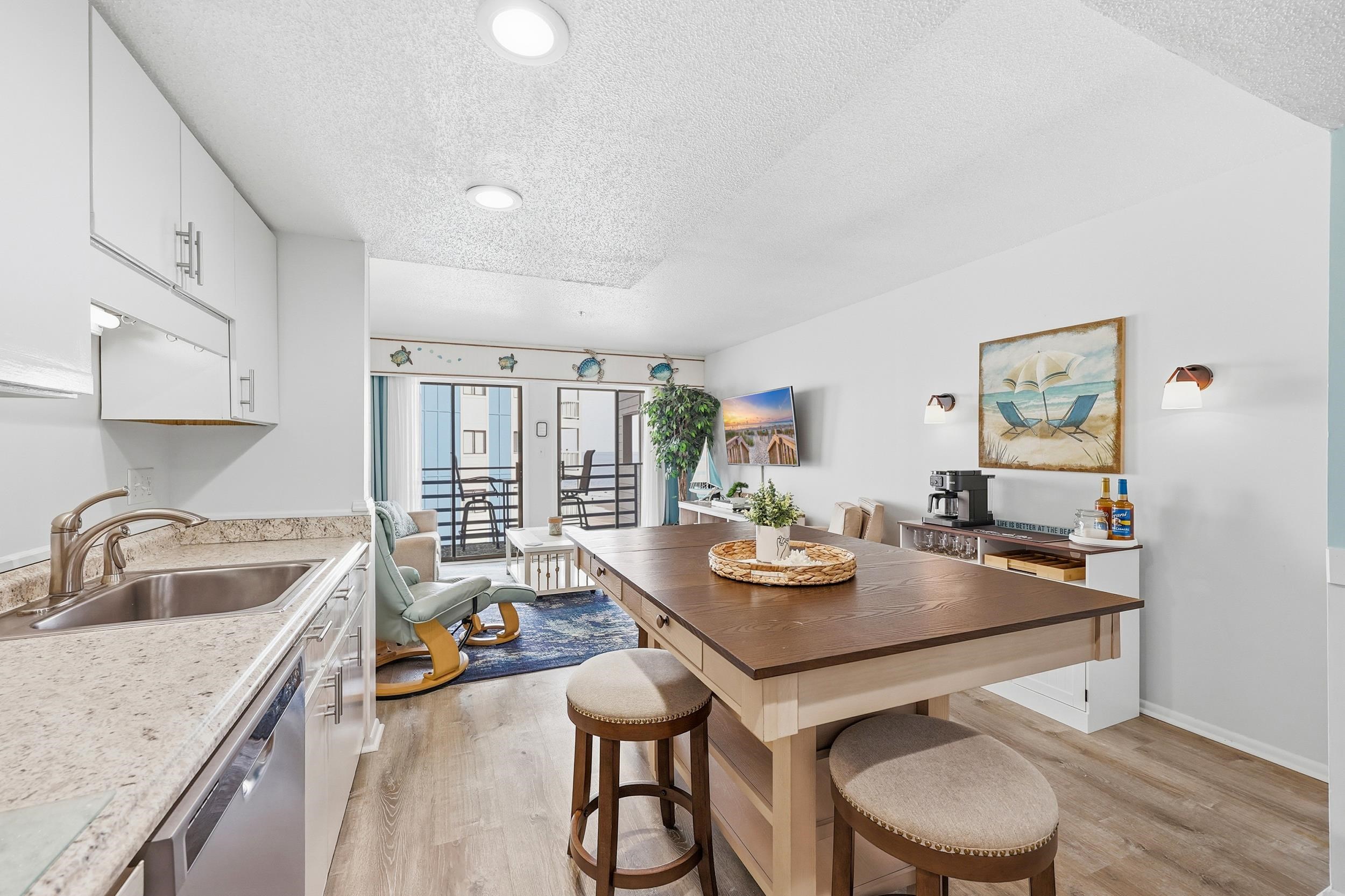 920 North Waccamaw Drive, Unit 2305 Murrells Inlet, SC 29576 - Photo 8 of 40 Kitchen with white cabinetry, a textured ceiling, light wood finished floors, stainless steel dishwasher, and a kitchen bar