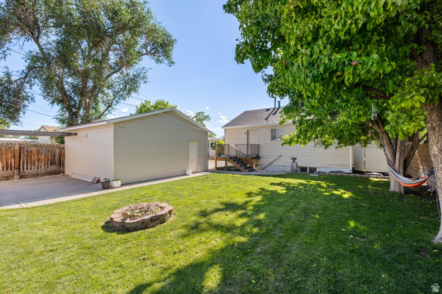 594 850 West Provo, UT 84601 - Photo 14 of 33 Expansive backyard featuring a manicured lawn, a detached garage with siding, and a stone-lined fire pit
