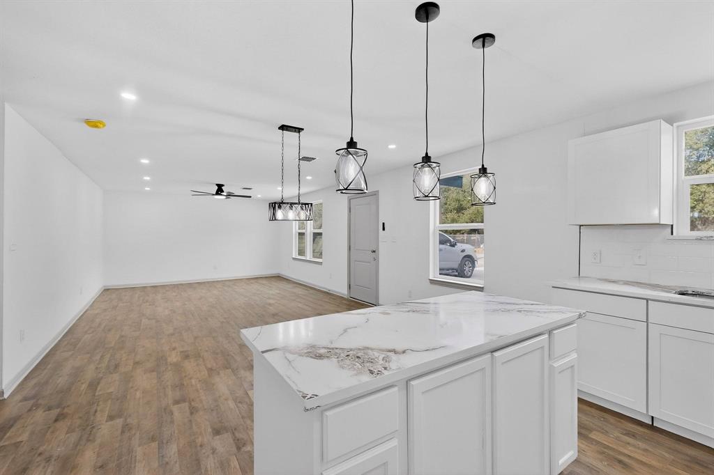 5650 Forney Road Dallas, TX 75227 - Photo 12 of 39 a view of a kitchen with kitchen island white cabinets and wooden floor
