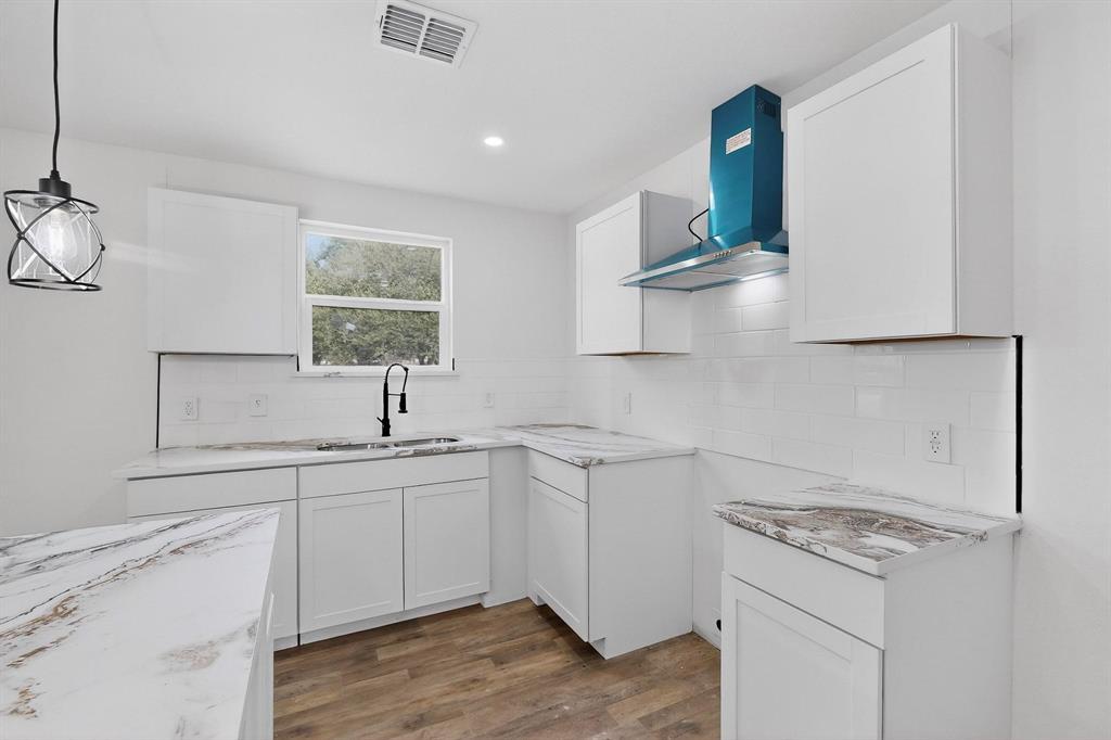 5650 Forney Road Dallas, TX 75227 - Photo 17 of 39 a kitchen with a sink dishwasher stove and white cabinets with wooden floor