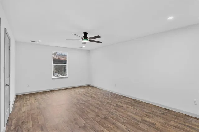 a view of a big room with wooden floor and windows