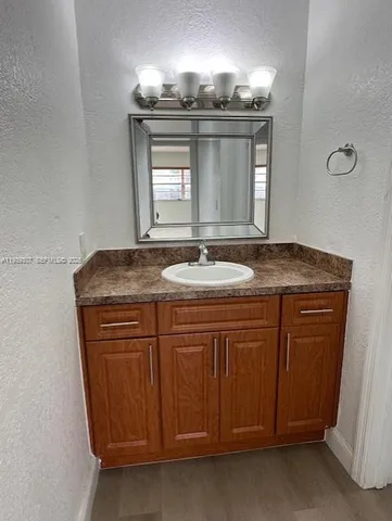 a bathroom with a granite countertop sink a light fixture and a mirror